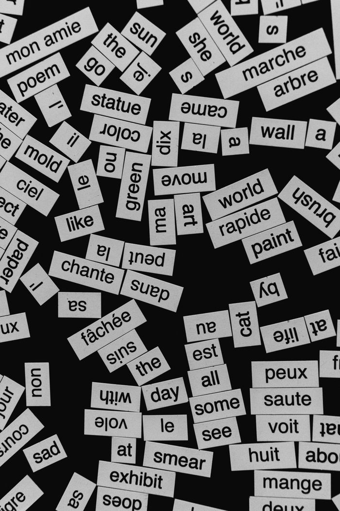 A close-up of various word cutouts on a black background, featuring different languages.