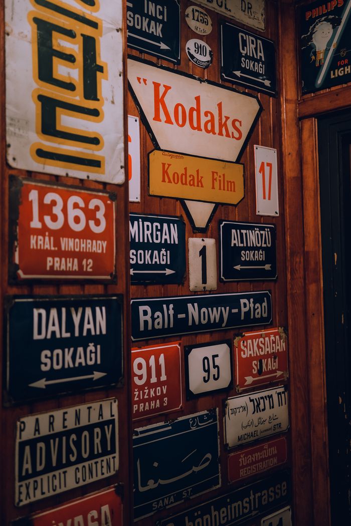 Colorful assortment of vintage street signs displayed on a wall indoors.