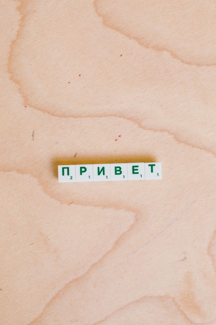 Wooden surface displaying Scrabble tiles with Cyrillic letters spelling 'Привет'.