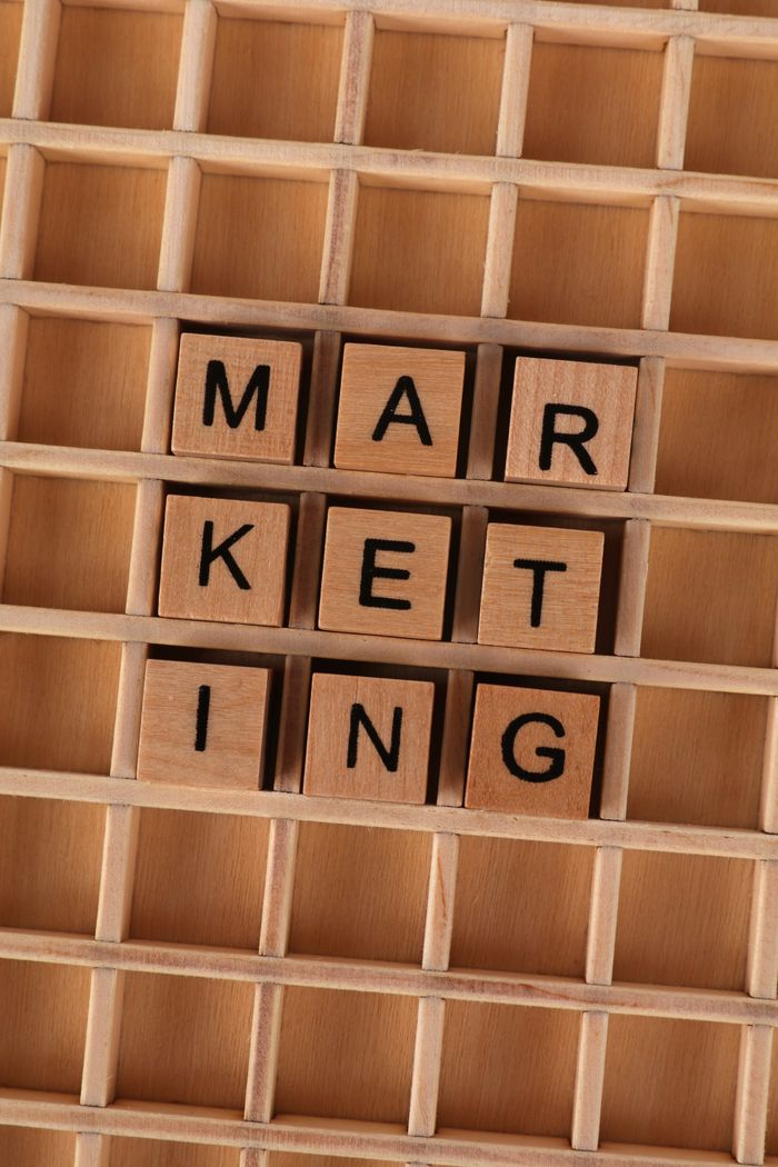 Wooden letter tiles arranged to spell 'marketing' on a wooden grid, depicting business strategy.